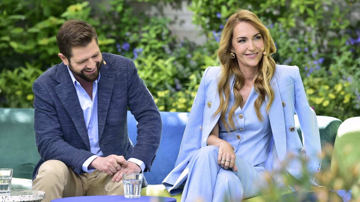 Mateusz Lisiecki-Waligórski i Magdalena Waligórska-Lisiecka podczas występu w programie „Pytanie na śniadanie”. Para siedzi na kanapie w plenerowym studiu otoczonym zielenią. Mężczyzna w granatowej marynarce śmieje się, patrząc w dół, natomiast kobieta w jasnoniebieskim garniturze uśmiecha się do rozmówców. Swobodna atmosfera i letnia sceneria podkreślają lekki charakter rozmowy.